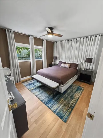 Spacious primary bedroom with warm wood floors and abundant natural light