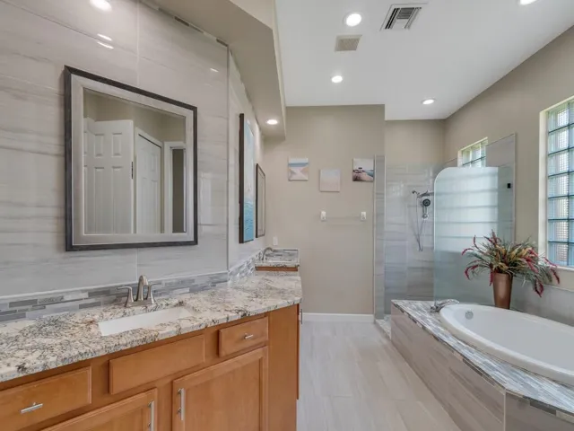 Remodeled primary bathroom with marble tiled walls