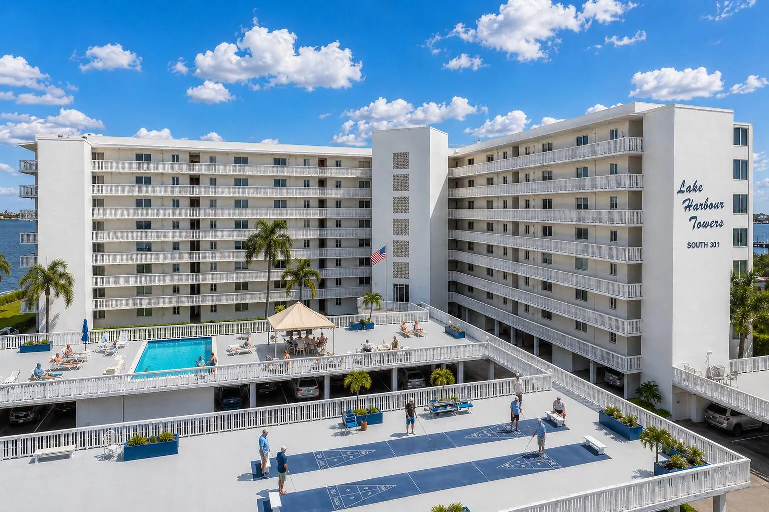 Community Amenities – Elevated deck featuring pool, shuffleboard, and gathering spaces. NOTE: This image includes virtual enhancement for illustrative purposes.