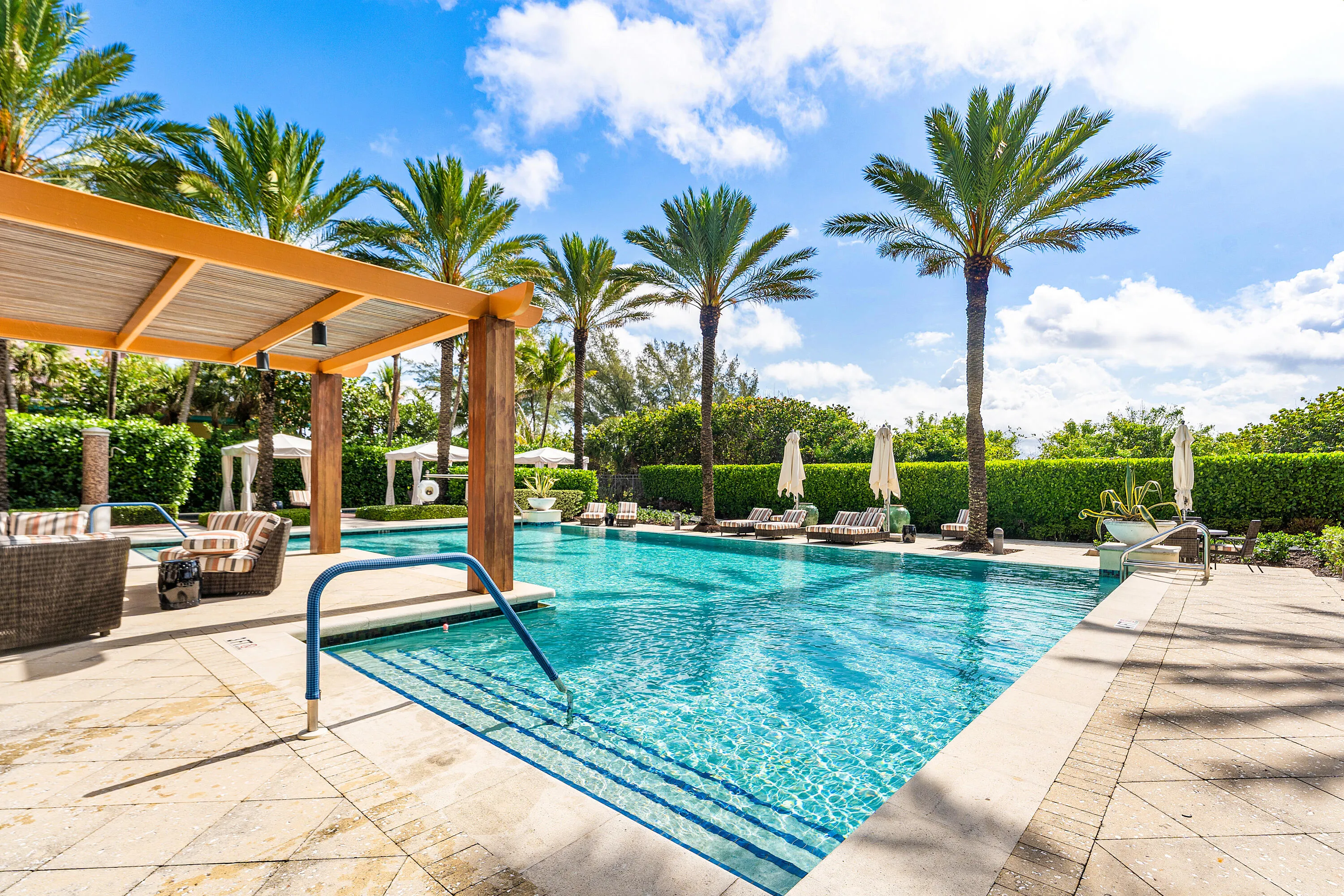 Resort style pool with lounge chairs, cabanas and BBQs