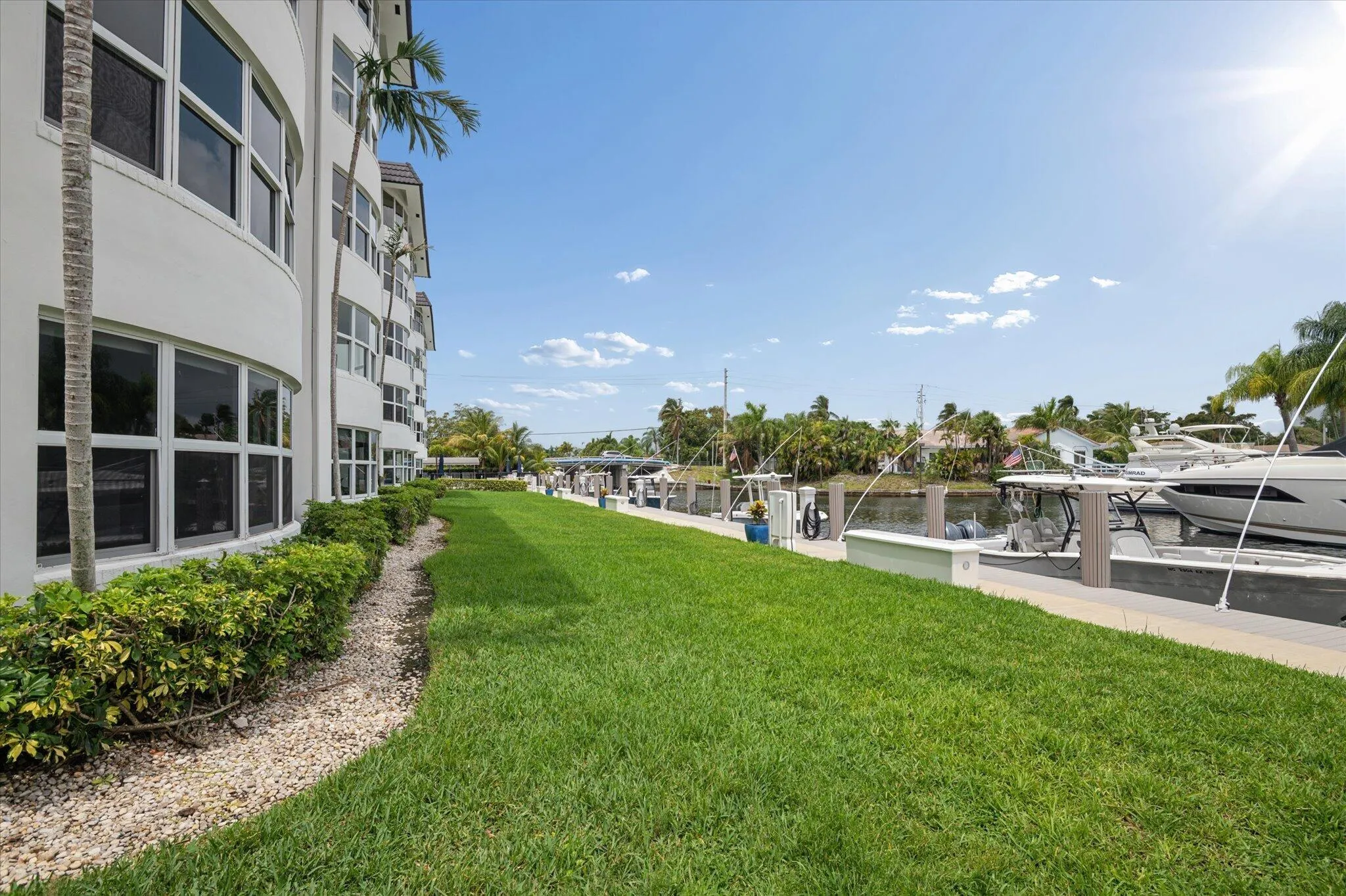 Lush green space leading to dockage along a deep-water canal.