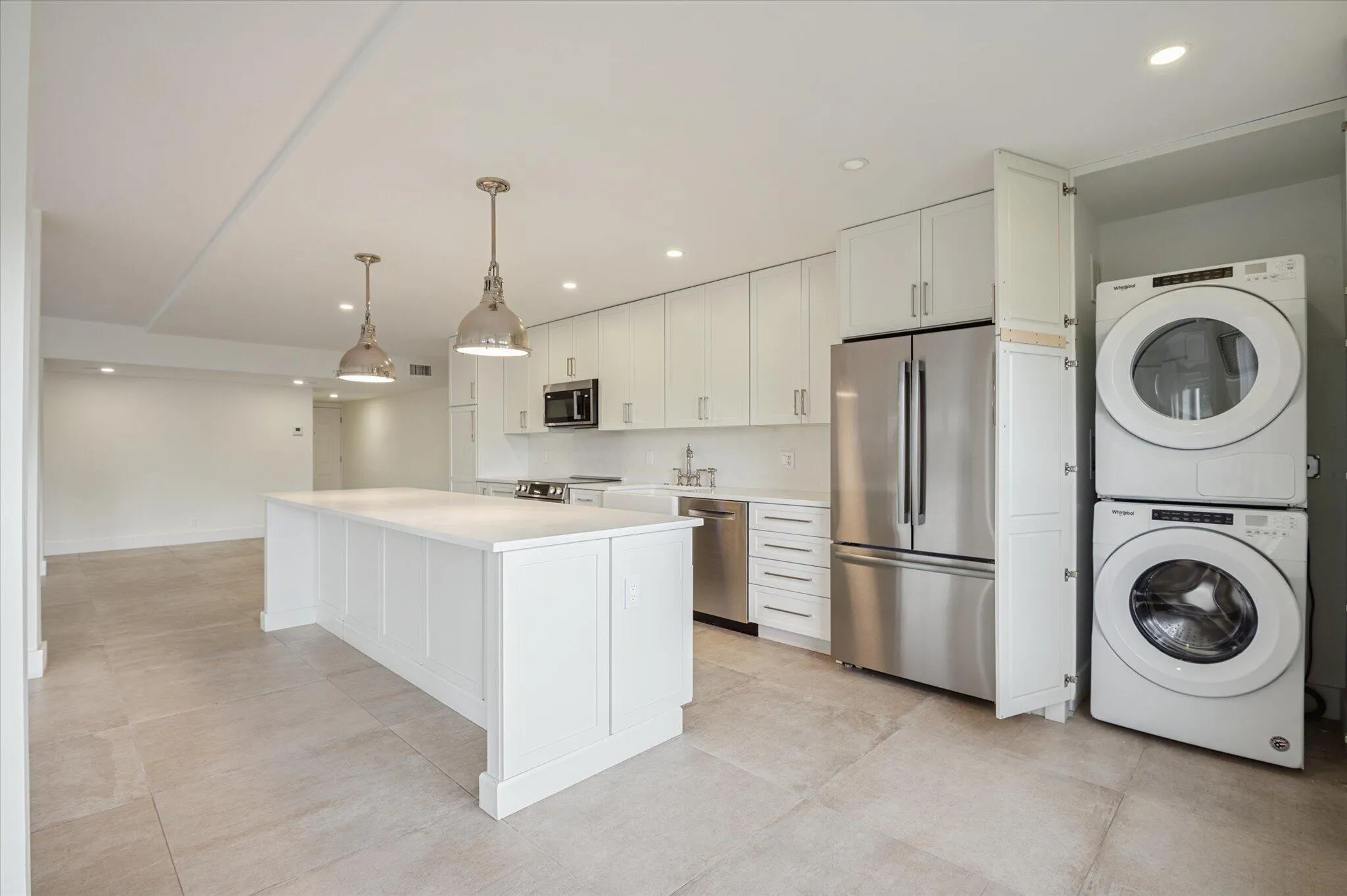 Designer kitchen featuring quartz countertops, pendant lighting, and ample storage and full size laundry washer and dryer.
