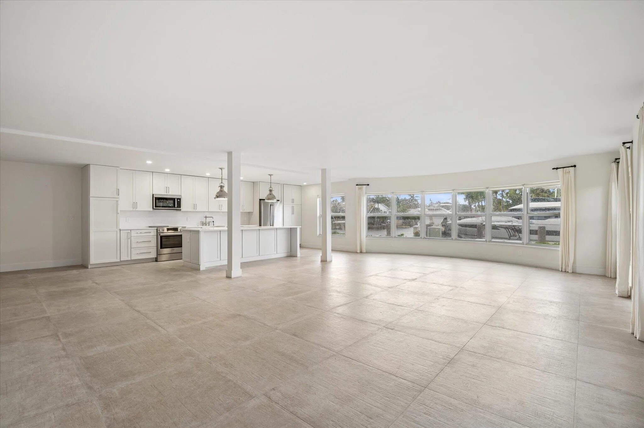 Expansive living space with a wall of bay windows showcasing panoramic canal views—this oversized 1,835 sq ft layout offers exceptional versatility, allowing for multiple dining and seating configurations rarely found in a 2BR/2BA condo.