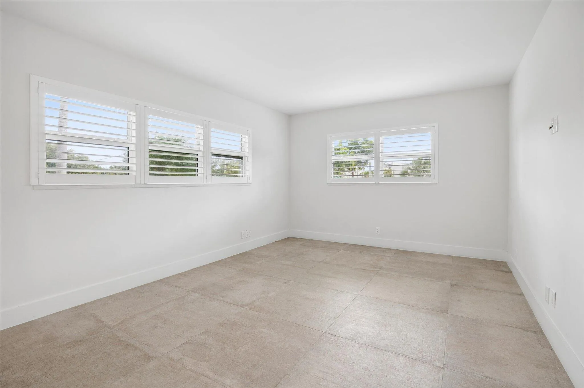 Bright and comfortable primary ensuite bedroom with clean white plantation shutters for privacy.