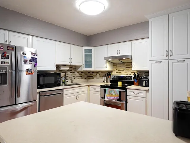 Updated kitchen featuring modern cabinetry, backsplash, and ample counter space