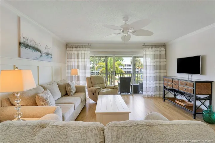 Bright open living space designed for relaxed Florida living with beautiful natural light, wood-look flooring, elegant trim work, and easy indoor-outdoor flow to the oversized lanai.