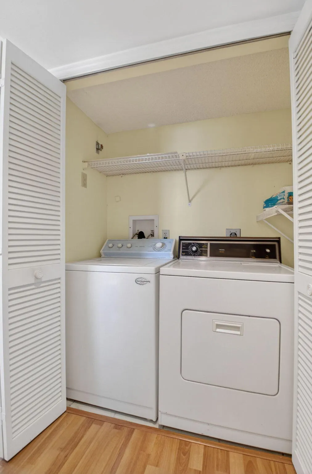Full-size laundry area with shelving and storage space for everyday convenience.