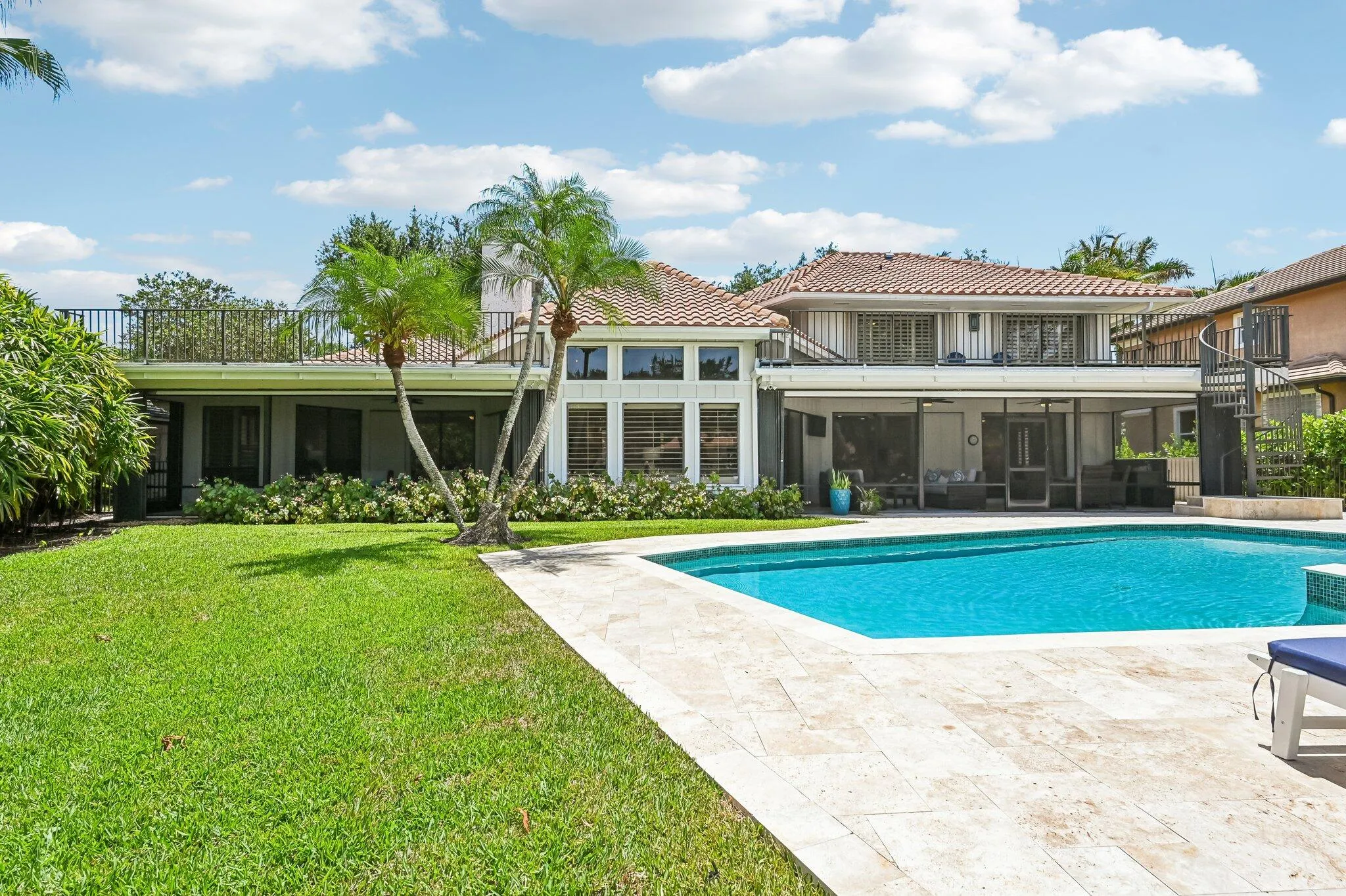 The outdoor living area is exceptional, featuring two screened lanais, a spacious backyard, pool and spa, and an expansive open deck surrounded by lush tropical landscaping—perfect for resort-style living.