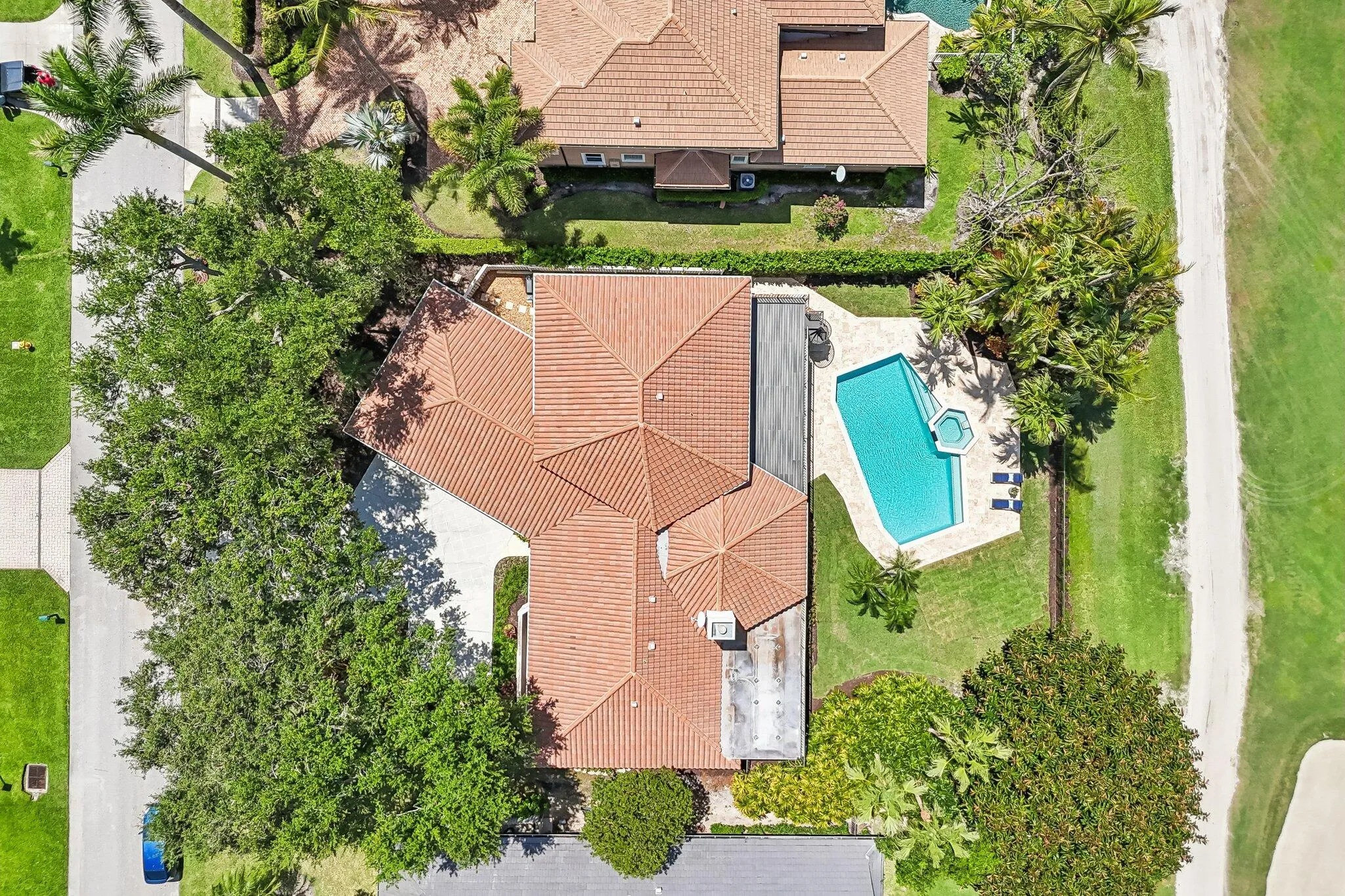 Aerial view showcases the 2020 tile roof, expansive yard, and lush tropical landscaping set along the prestigious Match Course.