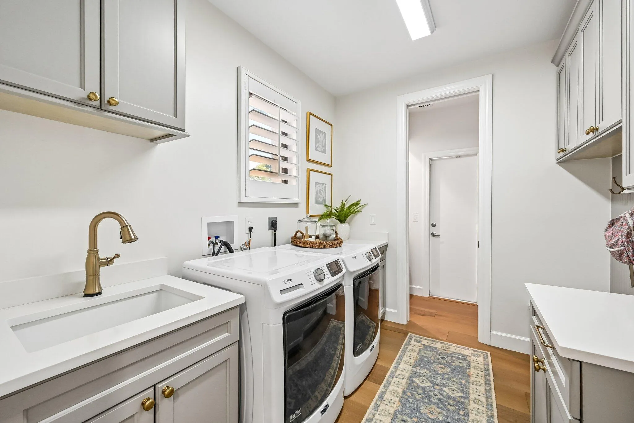 The renovated laundry room is thoughtfully designed with a drop zone, built-in bench, and hooks, conveniently located just off the garage for everyday functionality.