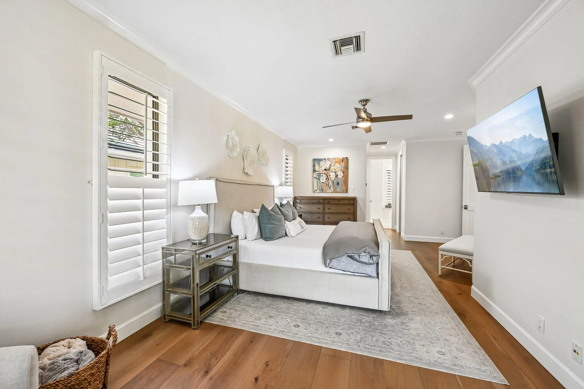 The spacious primary suite offers a private sitting area, elegant plantation shutters, and dual his-and-her closets for exceptional comfort and organization.