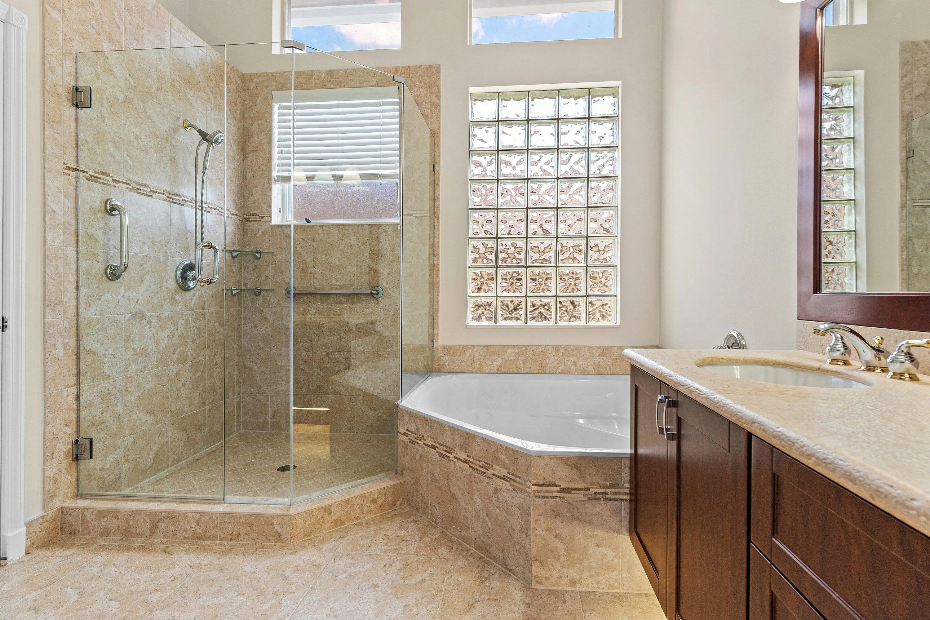 Primary Bathroom with frame less shower doors, separate tub and dual sinks