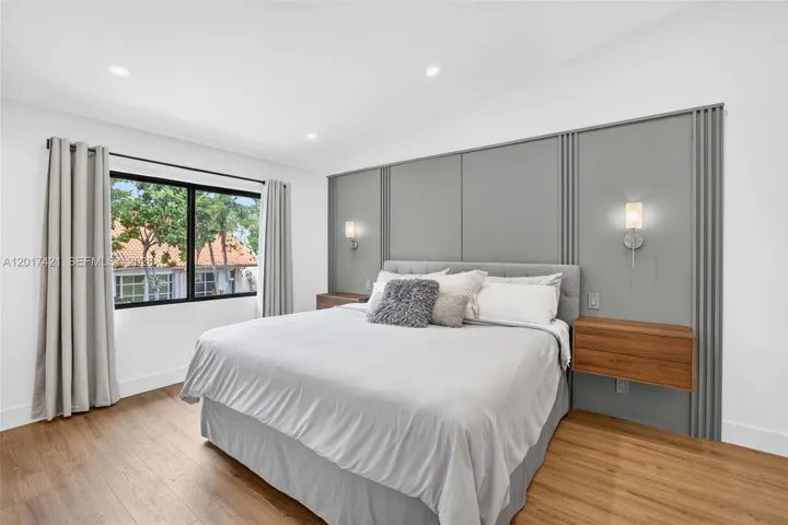 Primary bedroom w/ attached nightstands, feature wall and reading sconces - overlooks front of property
