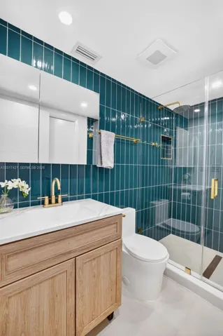 Upstairs guest bathroom (also en suite for one bedroom). Beautiful wall tile and vanity / medicine cabinet. Frameless shower enclosure