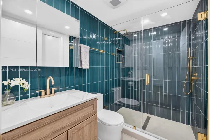 Upgraded bathroom w/ gorgeous finishes, rain shower head & handheld, tile to the ceiling, frameless shower door & medicine cabinet