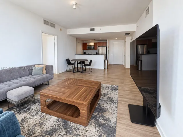 Open-concept main living area featuring wood-finish flooring, recessed ceiling lighting, and a kitchen equipped with stainless steel appliances and wood cabinetry