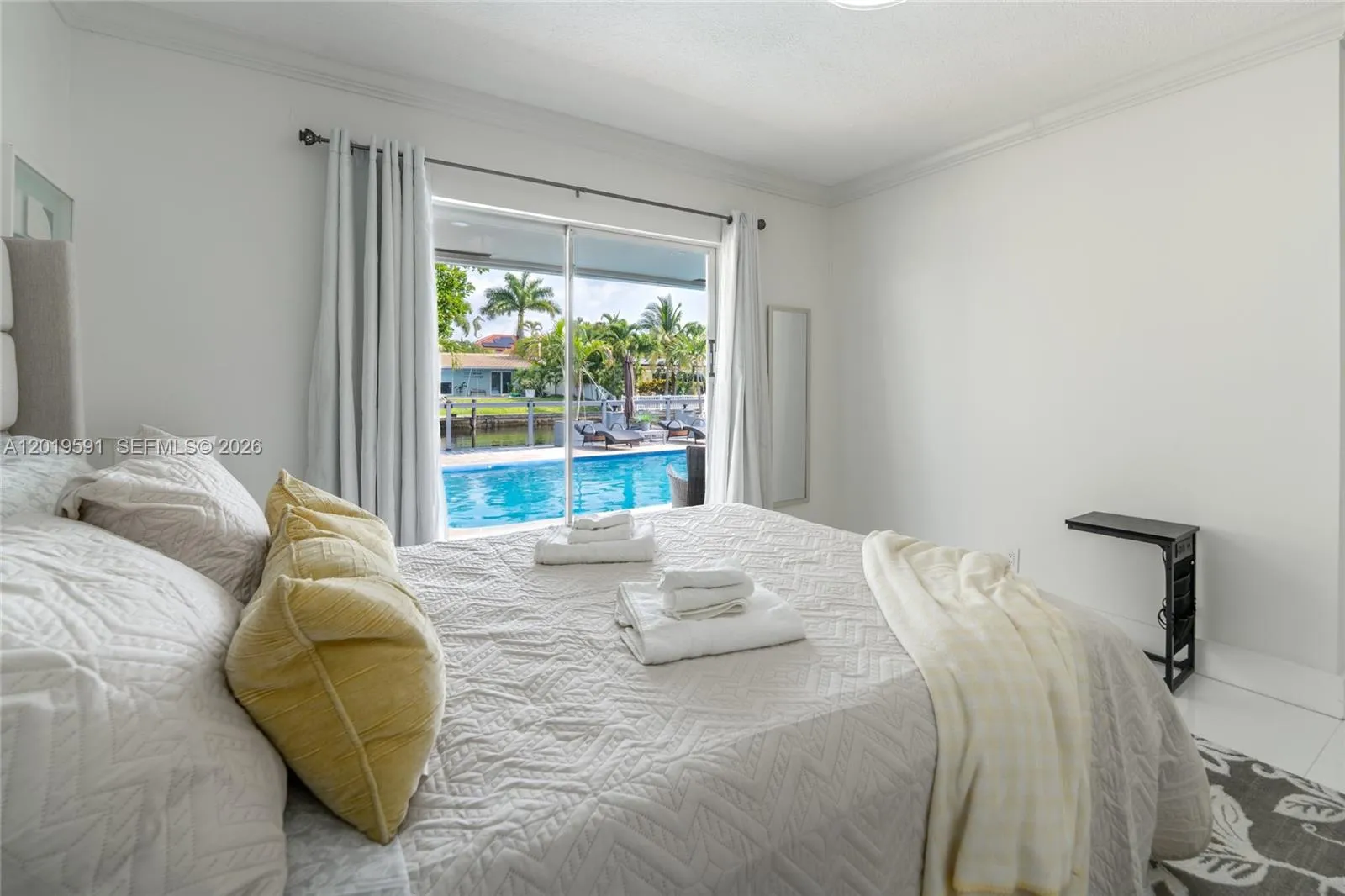 Bright pool-view bedroom featuring comfortable accommodations, modern styling, and tranquil natural light.