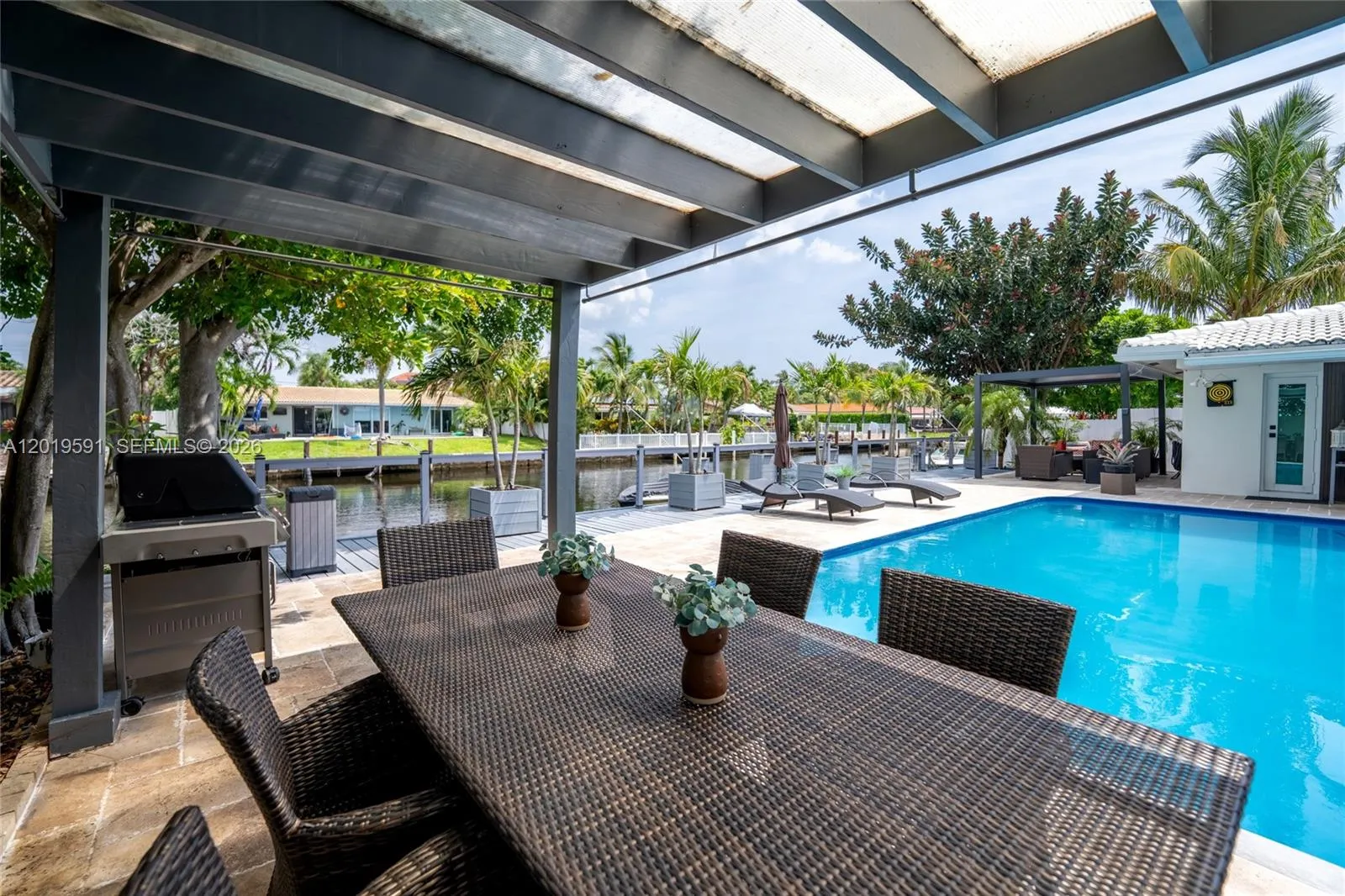 Covered waterfront outdoor lounge with heated pool views, tropical ambiance, and resort-style relaxation.