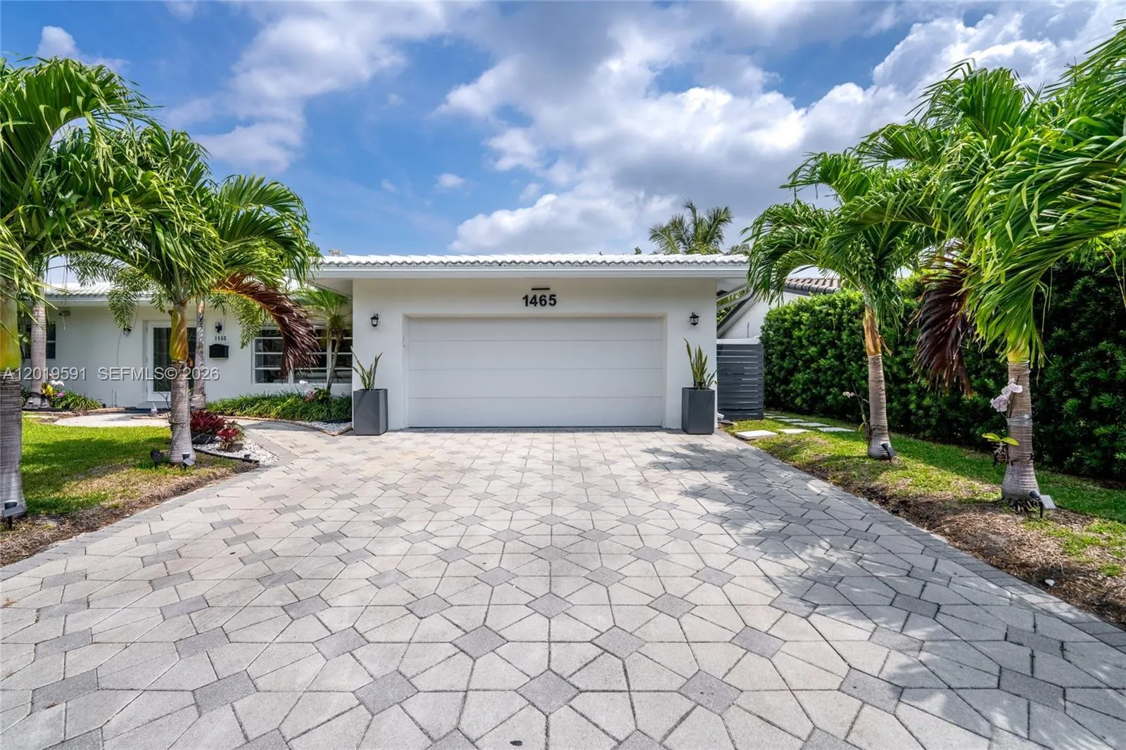 Beautiful tropical waterfront home with spacious driveway, palm trees, and luxury curb appeal.