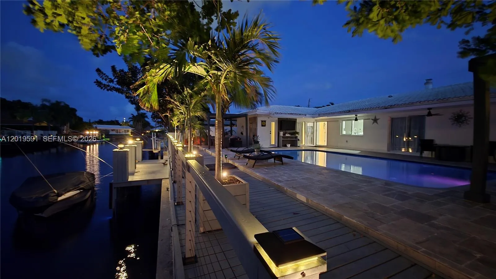 Stunning nighttime pool view with tropical lighting, private waterfront setting, and luxury outdoor living.