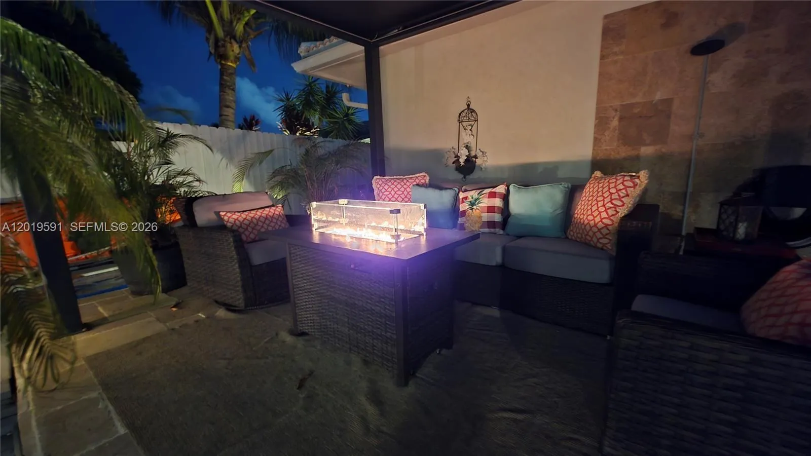 Cozy outdoor fire pit seating with tropical landscaping and elegant nighttime resort-style atmosphere.