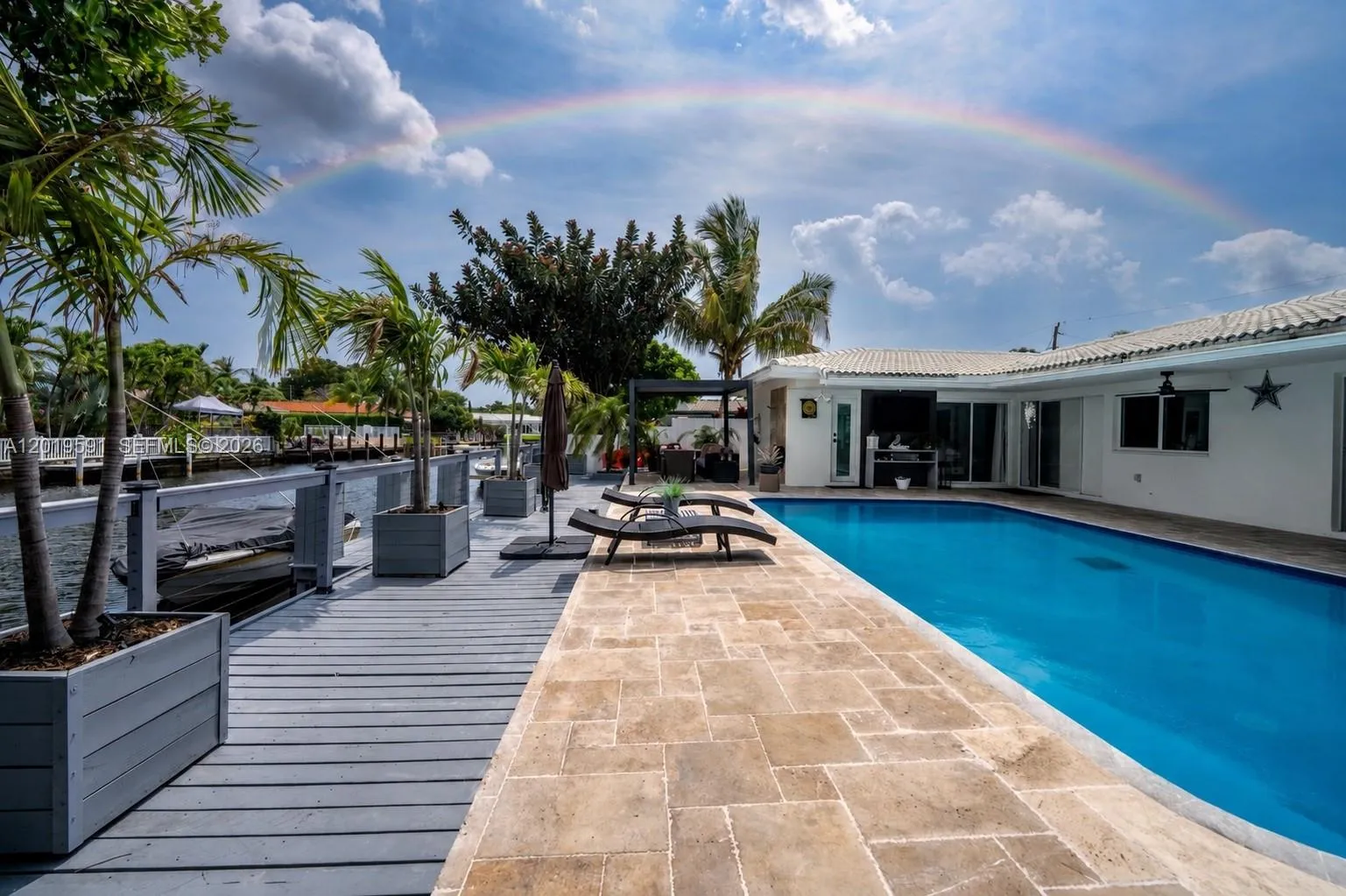 Private heated in-ground pool with spacious deck, tropical landscaping, and luxury outdoor entertainment area.