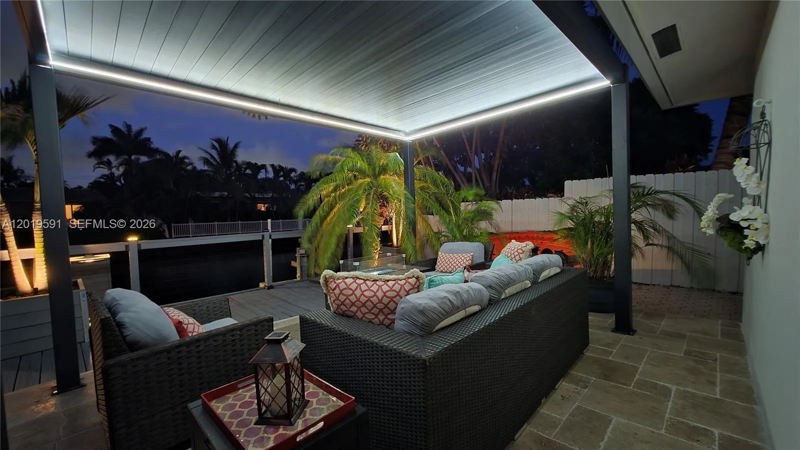 Covered outdoor lounge with LED lighting, waterfront views, and modern luxury evening atmosphere.