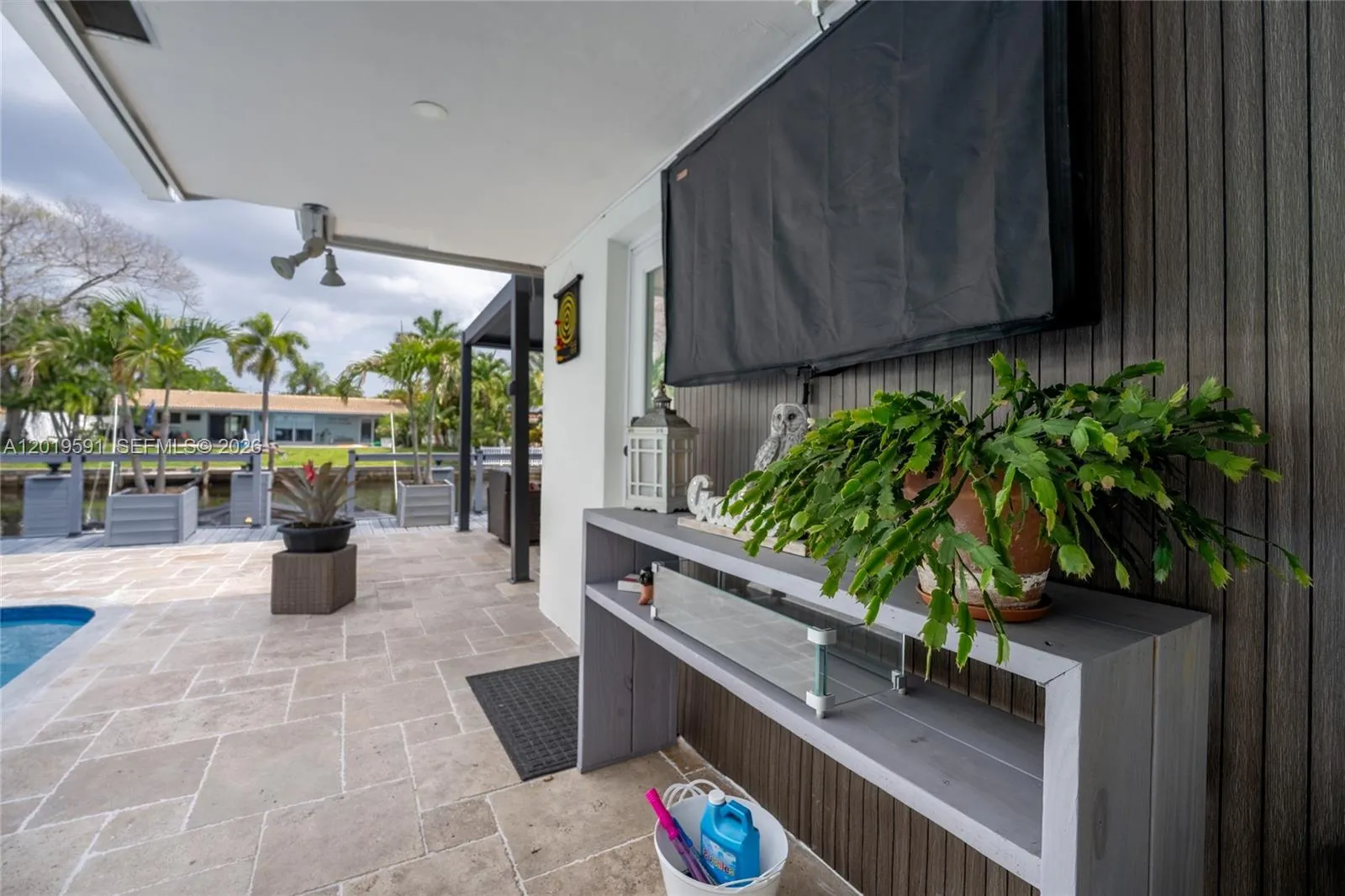 Modern outdoor entertainment area with mounted TV, lounge space, and seamless indoor-outdoor living.
