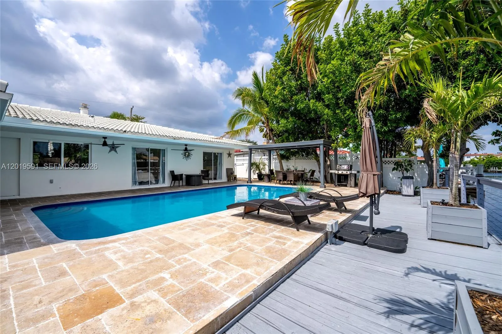 Resort-style heated pool with expansive deck, lounge seating, and tropical outdoor entertainment space.