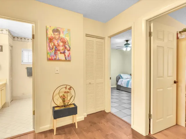 Bedroom hallway with wood-look flooring, neutral walls, and multiple doorways leading to the bedroom wing and bathroom areas.