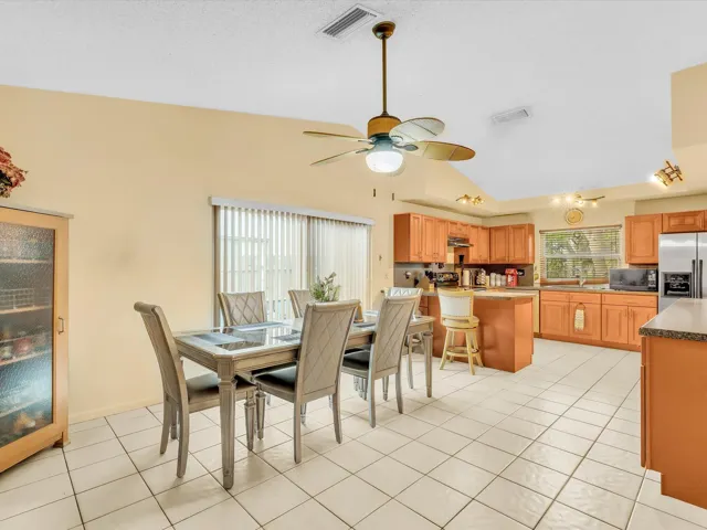 Dining area with tile flooring, ceiling fan, vertical blinds, and convenient access to the kitchen and living space.
