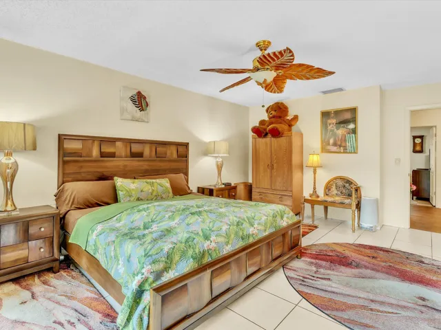 Spacious primary bedroom with tile floors, ceiling fan, neutral walls, large window, and a comfortable room layout.