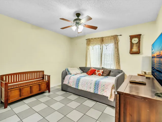 Bedroom 2 with tile flooring, ceiling fan, window, closet doors, and a clean neutral layout in the 3-bedroom home.