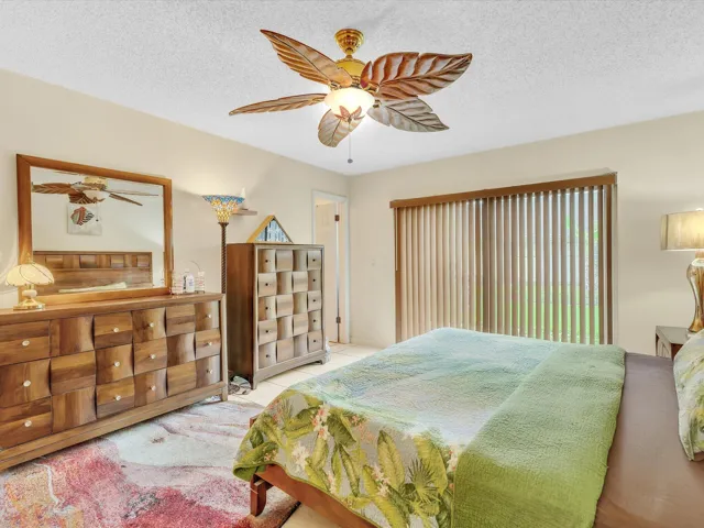 Primary bedroom view showing sliding door coverage, tile flooring, ceiling fan, and an open room layout.