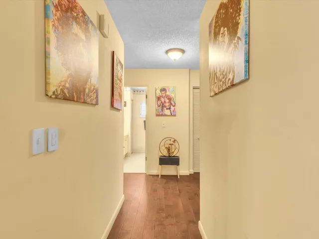Interior hallway with neutral walls, wood-look flooring, and access from the main living area to the bedrooms and bathrooms.