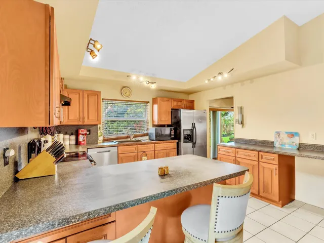Kitchen view focused on cabinet storage, breakfast bar counter space, stainless refrigerator, and open dining connection.