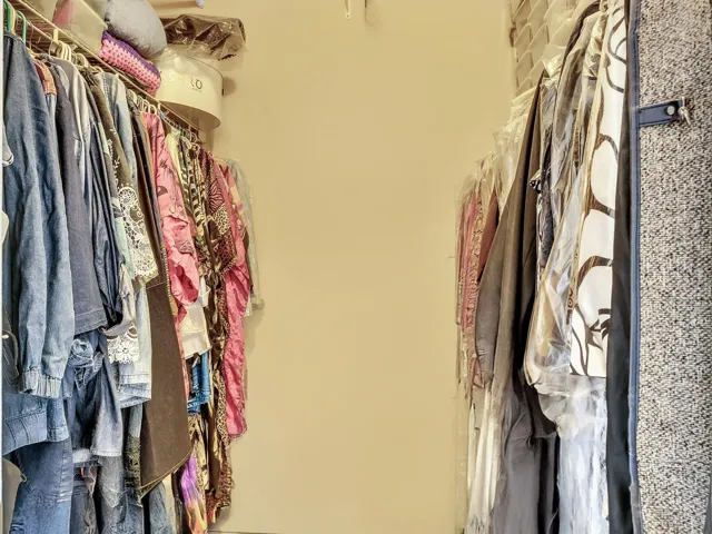 Primary bedroom walk-in closet with hanging storage, shelving, and organized closet space.