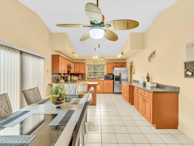 Kitchen with wood cabinetry, stainless steel appliances, tile flooring, breakfast bar seating, and functional counter space.