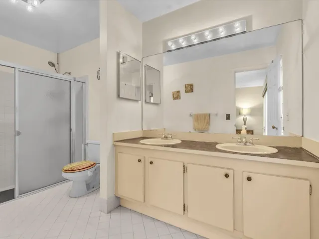 Primary bathroom with vanity, mirror, walk-in shower, toilet, tile flooring, and neutral finishes.