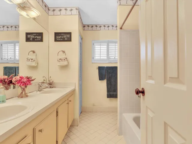 Second bathroom view with vanity, mirror, tile floor, window, and tub-shower area for the secondary bedrooms.