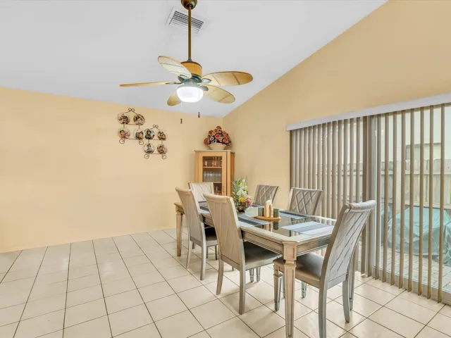 Dining area with sliding glass doors leading toward the backyard, plus tile floors, ceiling fan, and an open layout.