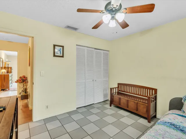 Bedroom 2 angle showing closet doors, entry doorway, ceiling fan, tile flooring, and a practical room layout.