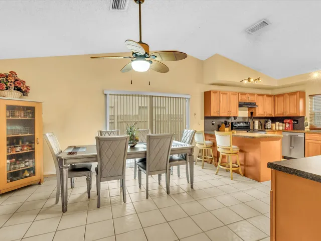 Open dining and kitchen area with tile flooring, breakfast bar seating, and a smooth connection to the living room.