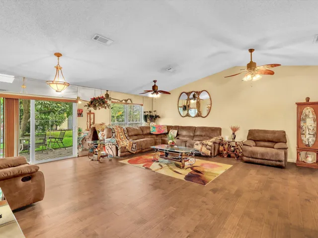 Bright living room with sliding glass doors, ceiling fan, and an open layout connecting the interior to the rear outdoor area.
