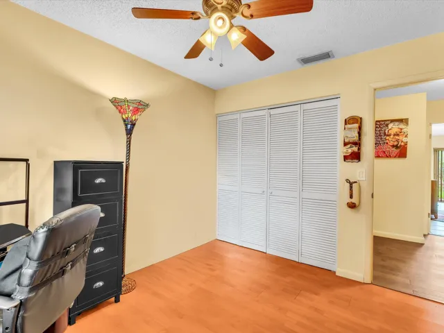 Bedroom 3 alternate view showing closet doors, ceiling fan, wood-look flooring, neutral walls, and natural light.