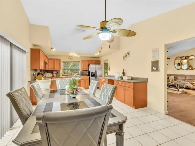 Kitchen and dining view showing breakfast bar seating, wood cabinets, stainless appliances, and open interior flow.