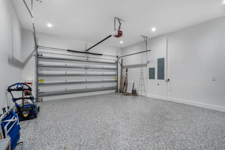 Two-car garage featuring decorative flake flooring and integrated EV charging.