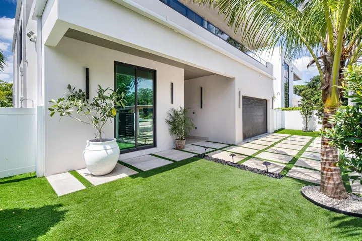 View of the grand front entrance framed by lush landscaping and manicured turf.