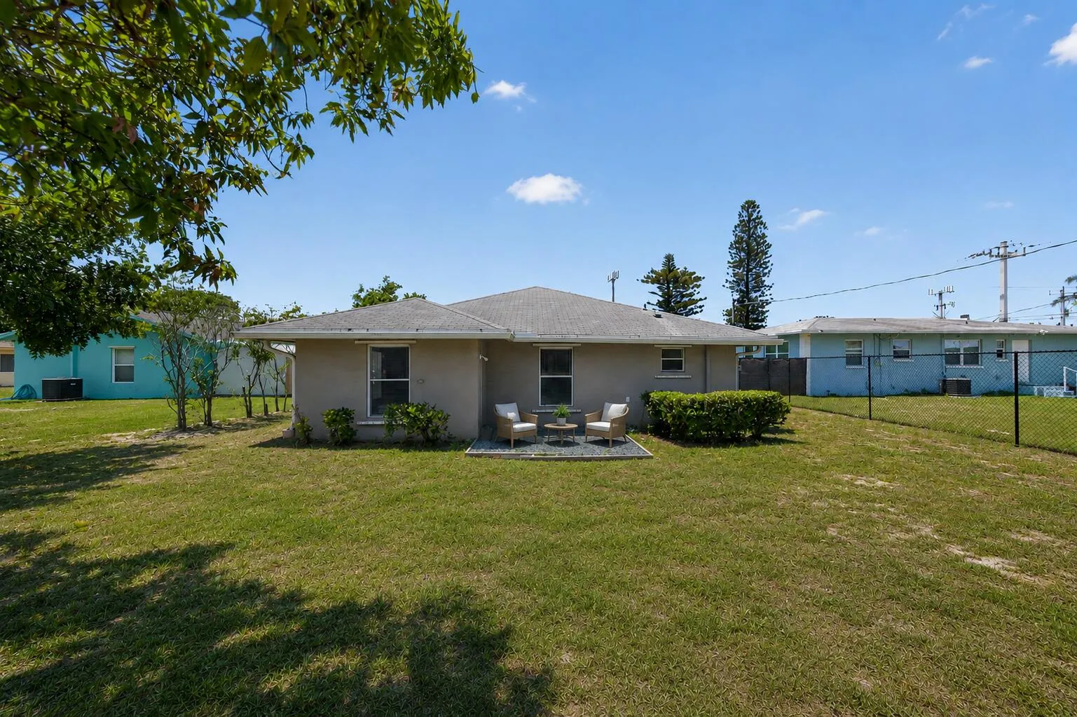 Private backyard retreat with plenty of green space and a cozy outdoor seating area perfect for relaxing. Virtually staged