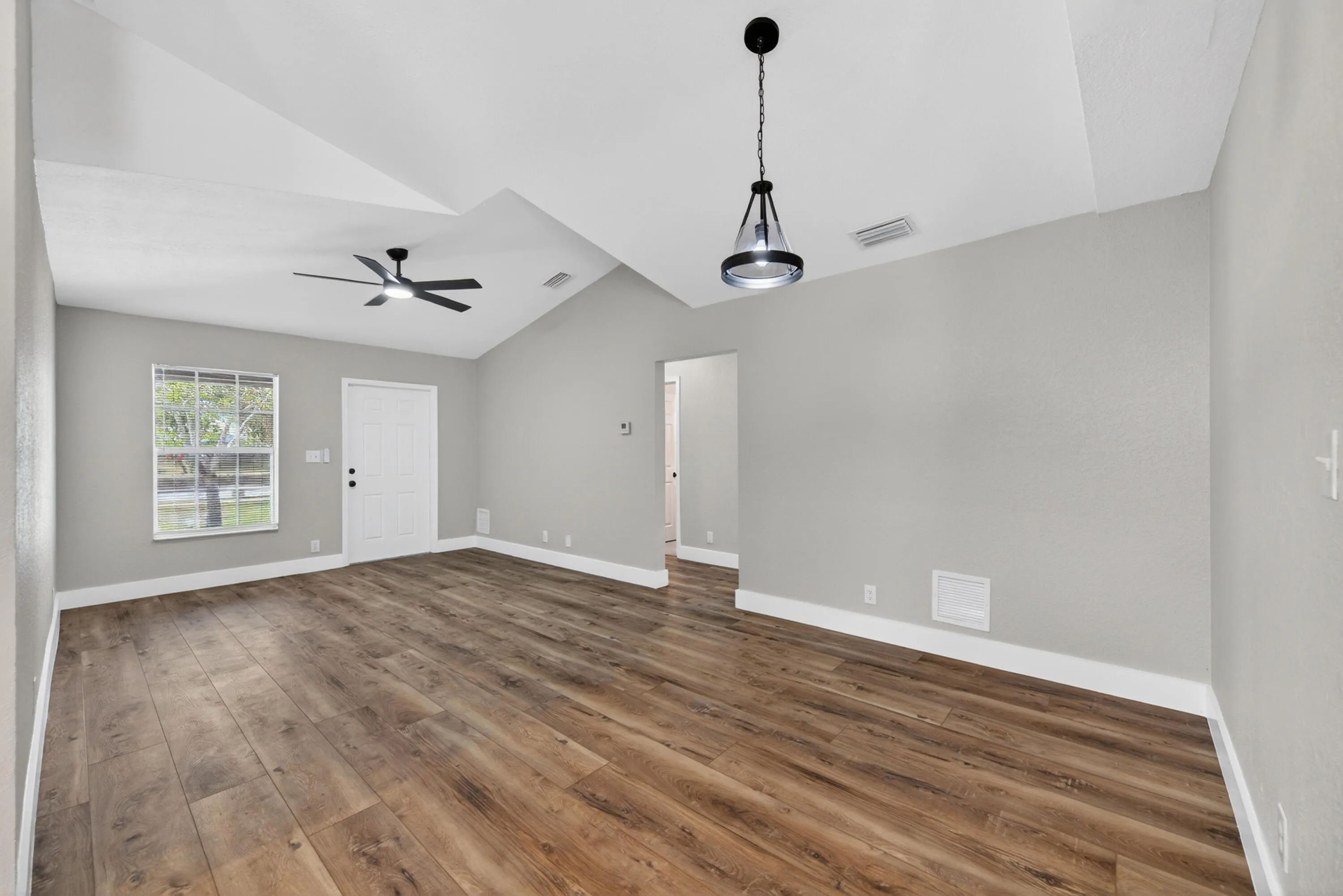 Spacious living and dining area featuring vaulted ceilings and an open layout